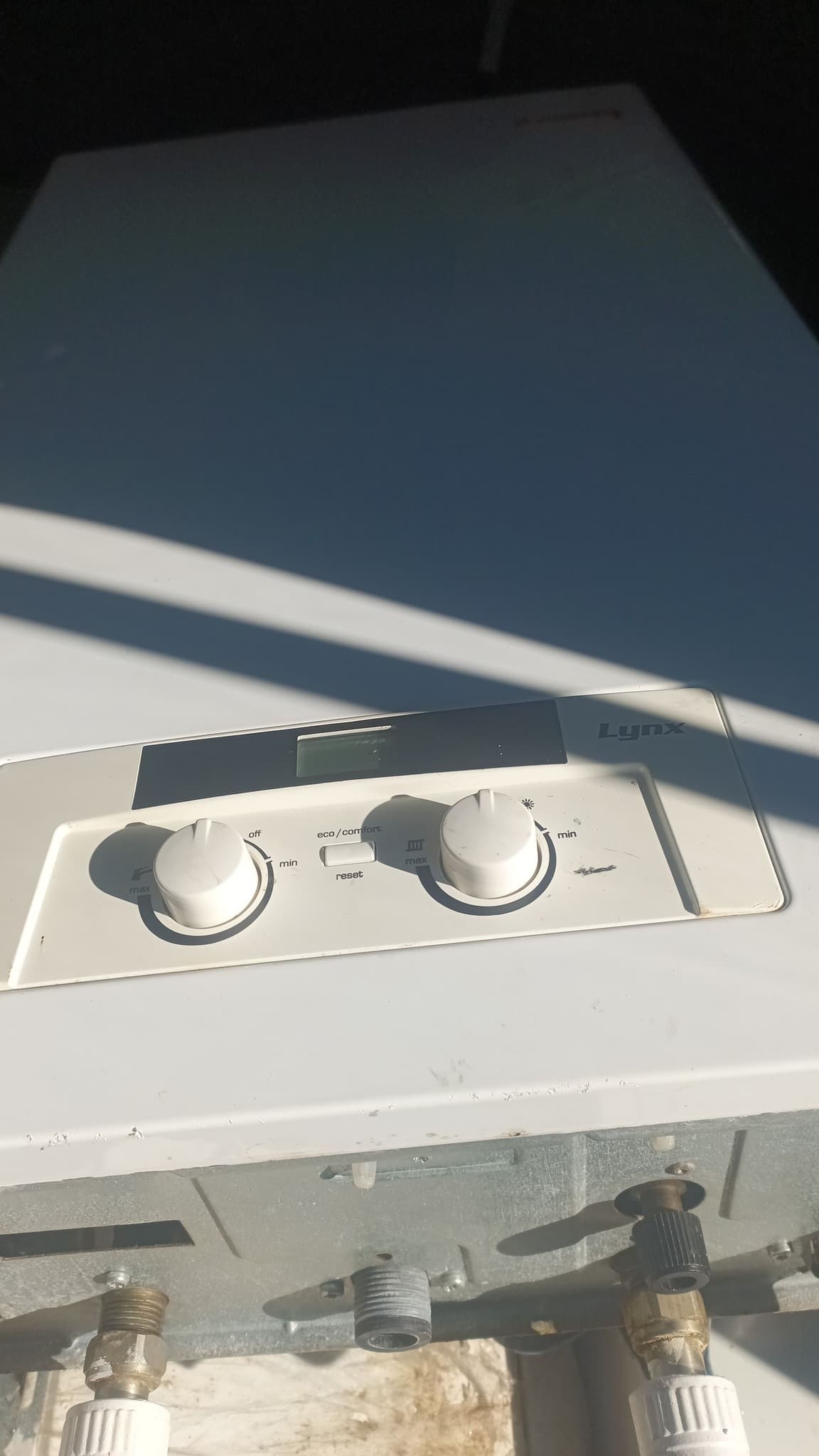 White Lynx boiler control panel with two knobs, a digital display, and bottom pipe connections.